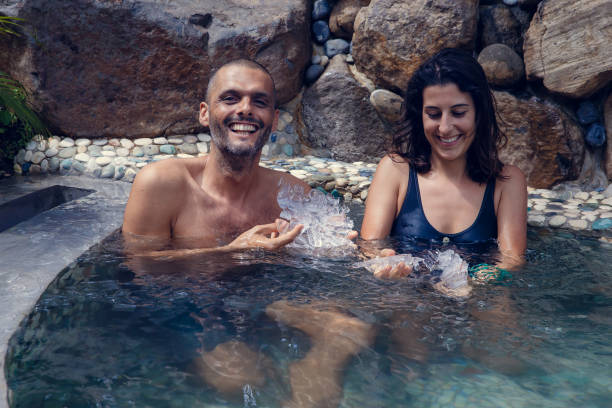 ung man och kvinna som har fritidsbad i vattnet fyllda med isbitar. multietniska par få cryo terapi utomhus under sommaren - ice bath bildbanksfoton och bilder