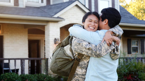 Young man and woman in uniform hug and smile A young woman in uniform smiles as she hugs a young man tightly. veterans returning home stock pictures, royalty-free photos & images