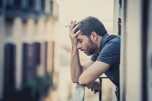 young man at balcony in depression suffering emotional crisis stock photo