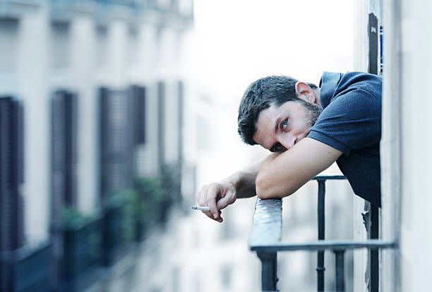 young man at balcony in depression suffering emotional crisis stock photo