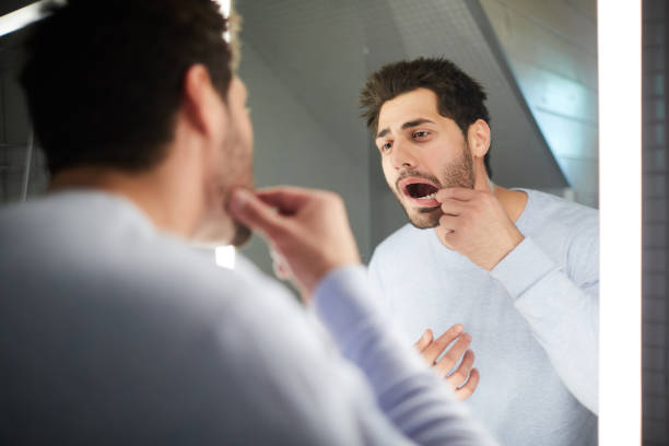 jongeman controleren tand in badkamer - mouth stockfoto's en -beelden