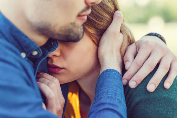 Young man comforting his girlfriend Unhappy young couple in the city park relationship problems stock pictures, royalty-free photos & images