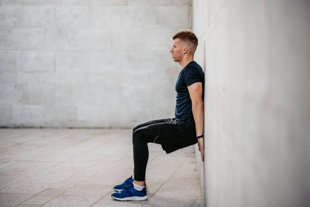 Young Man Doing The Wall Sit Exercise Outdoors stock photo