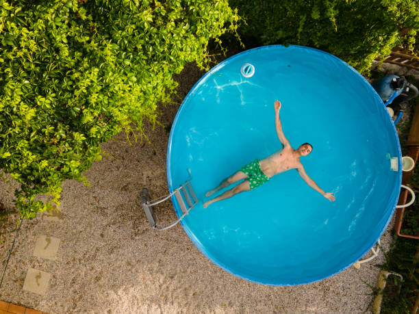 junger mann genießt entspannung im kleinen pool - pool rund stock-fotos und bilder