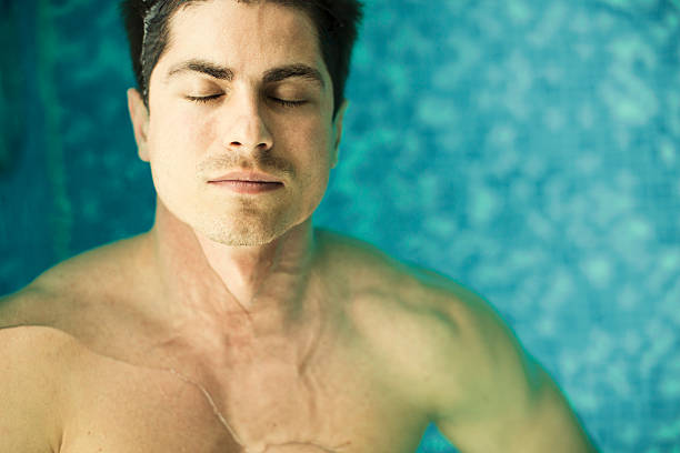 Young man floating in the swimming pool stock photo