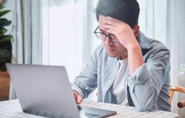 Young man getting frustrated over laptop stock photo
