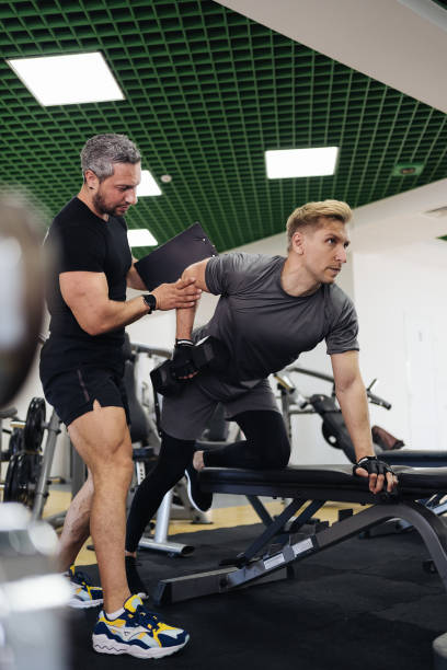 Young man has workout with personal trainer in the gym stock photo