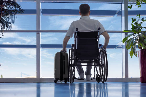 Young man in a wheelchair with luggage at the airport stock photo