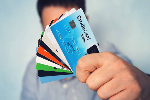 ung man i ljusblå skjorta visar många typer av kreditkort. affärsman i fritidskläder som håller i hand olika betalkort. bibba kort med biometriska scanner kort på toppen. banktjänster - typography scan bildbanksfoton och bilder