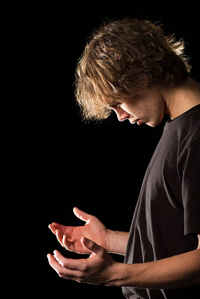 Young man in prayer with cupped hands stock photo
