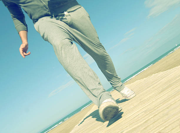 young man jogging on beach - a close up view stock photo