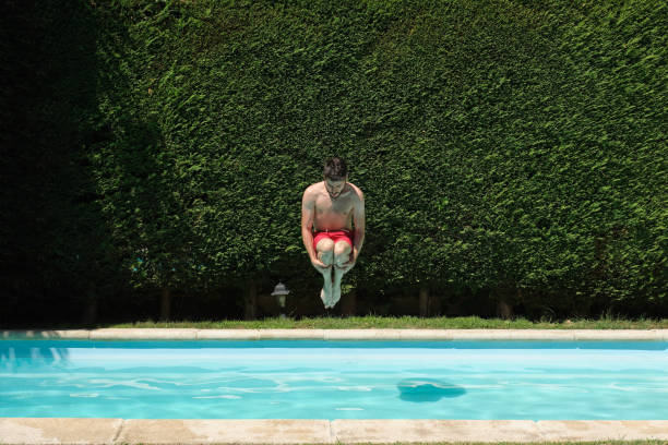 Young man jumping into a swimming pool. Summer concept. stock photo