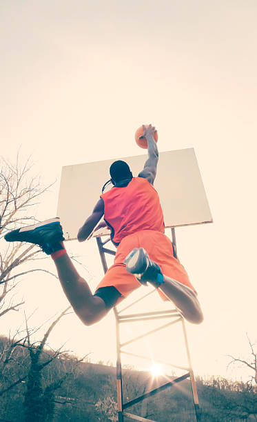 young man jumping to score hoop in basketball - basketball player back stockfoto's en -beelden