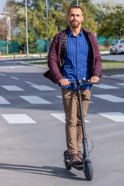 Young man on an electric scooter on pedestrian crossing stock photo