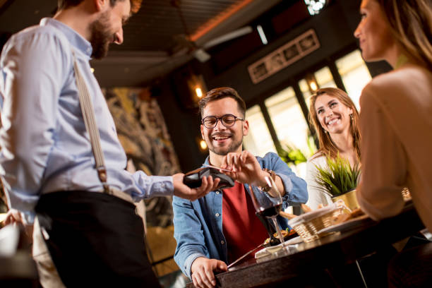 Young man paying with contactless credit card in restaurant after dinner stock photo