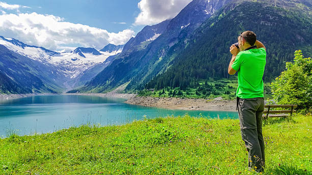 Young man photographingalpine lake, Austria stock photo