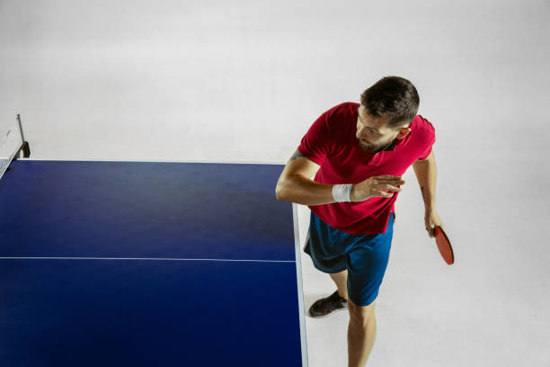 Young man plays table tennis on white studio background. Model in...