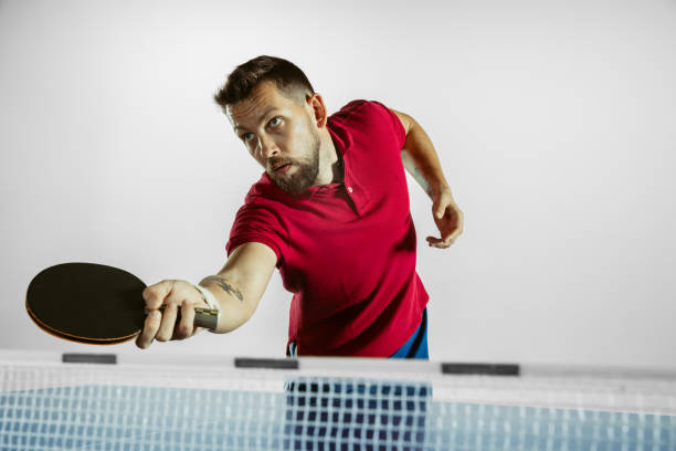 Strong. Young man plays table tennis on white studio background....