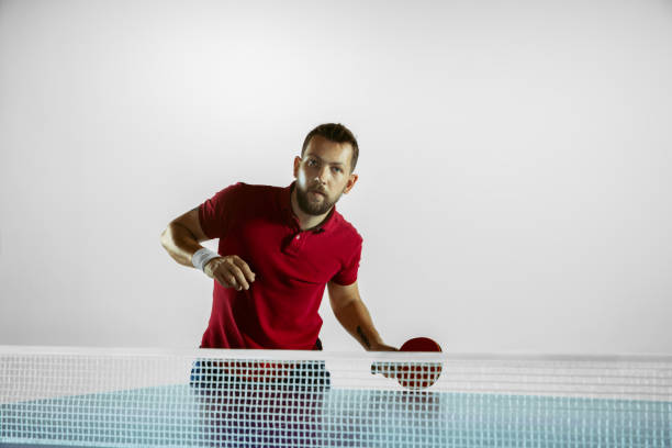 Rush. Young man plays table tennis on white studio background. Model...