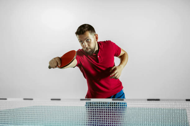Run. Young man plays table tennis on white studio background. Model...