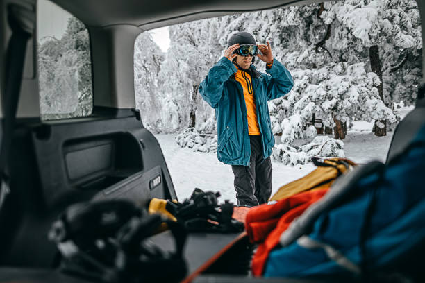 junger mann bereitet sich auf snowboarden vor - auto packen für den urlaub winter stock-fotos und bilder