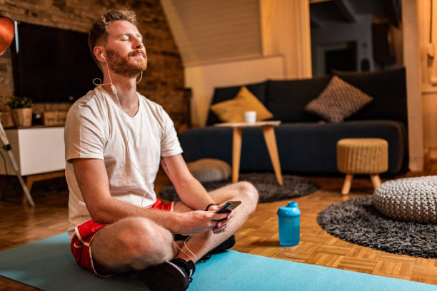 Young Man Relaxing At Home With Guided Meditation.