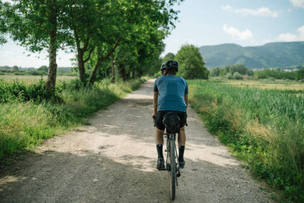 Young man rides bicycle through Tuscany countryside stock photo