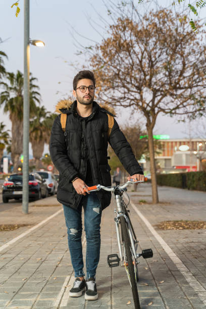 Young man riding bike in city street stock photo