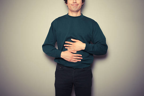 Young man rubbing his stomach stock photo