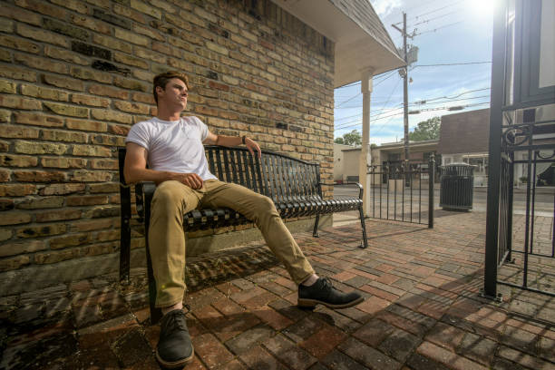 Young man sits on outside bench. stock photo
