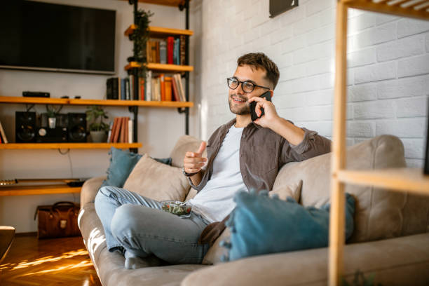 Young man sitting in couch, talking on his mobile phone. stock photo