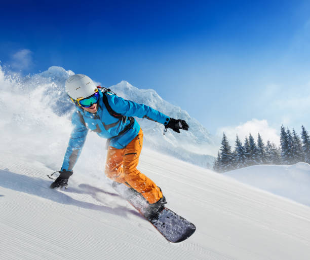 young man snowboarder running down the slope in alpine mountains - snowboard imagens e fotografias de stock