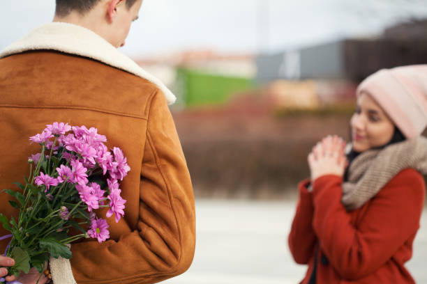 Young man surprising his girlfriend on Valentine's day stock photo