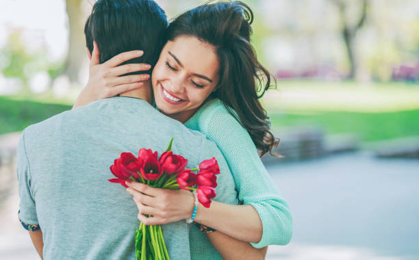 Young man surprising his girlfriend with bouquet of tulips stock photo