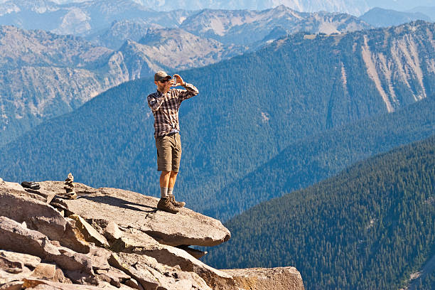 Young Man Taking a Picture With His Cell Phone Mount Rainier National Park, Washington, USA - September 28, 2014: A young man takes a picture with his cell phone while standing on a rock ledge on Burroughs Mountain. jeff goulden mount rainier national park stock pictures, royalty-free photos & images