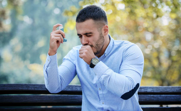 Young man treating asthma with inhaler. Health care concept stock photo