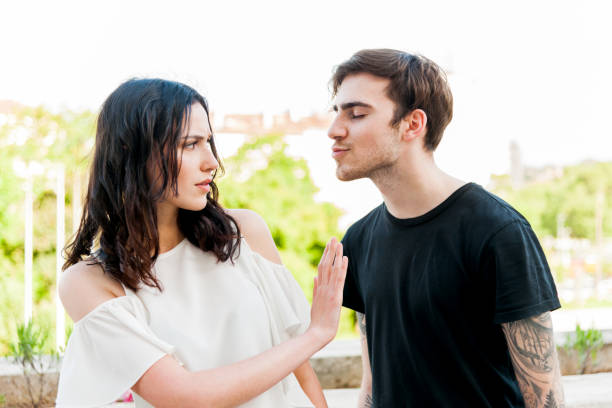 Young man trying to kiss a young woman stock photo