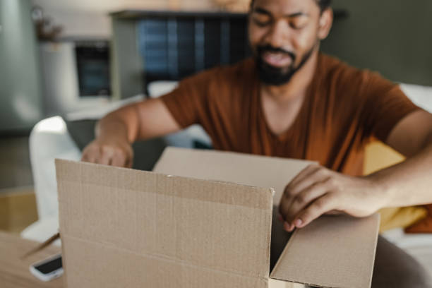 Young man unboxing online purchase in the living room stock photo
