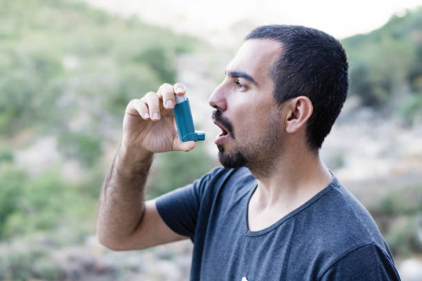 Young man using an asthma inhaler stock photo