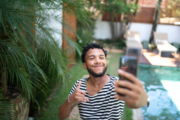 young man using mobile making a video at home - smartphone filming imagens e fotografias de stock