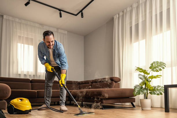 Young man using vacuum cleaner at home stock photo