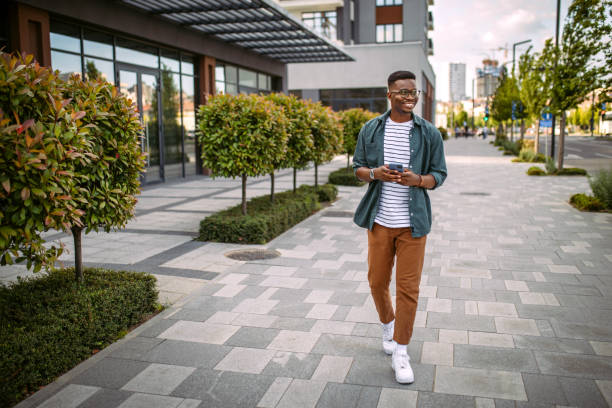 Young man walking down the street, using mobile phone stock photo