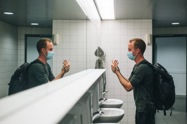Young man washes his hands in train station bathroom stock photo