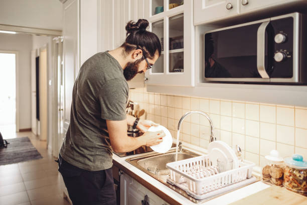 Young man washing dishes at home stock photo