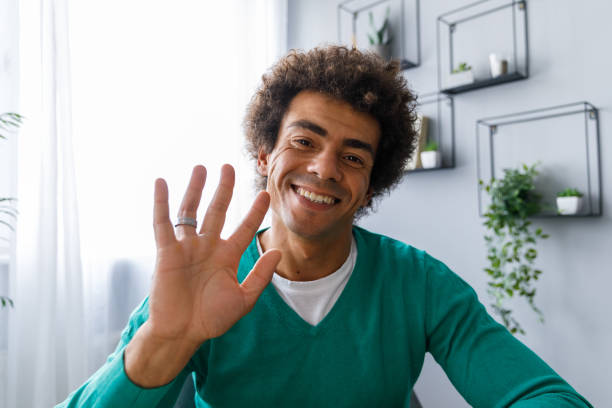Young man waving at camera as if he is on a video call stock photo