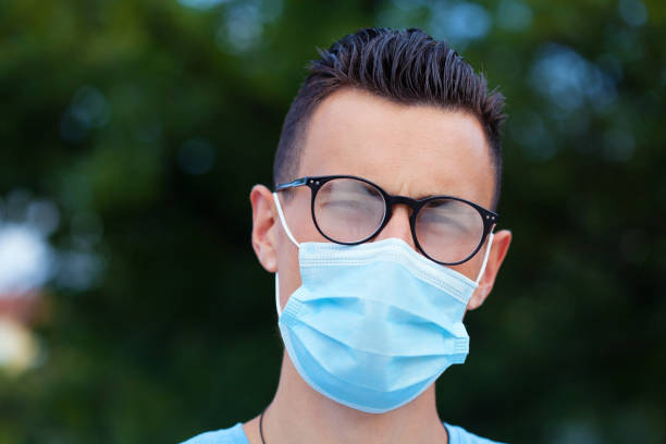 Young man wearing a protective face mask and eyeglasses stock photo