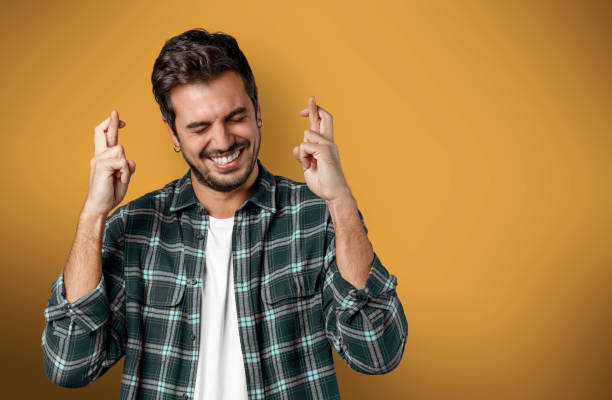 Young man with fingers crossed waits for good news stock photo