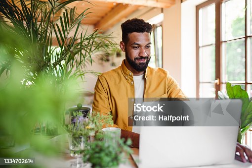 istock Young man with laptop and coffee working indoors, home office concept. 1334702614