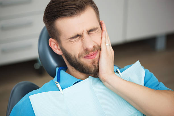 Young man with tooth pain sitting in a dentist's chair. stock photo