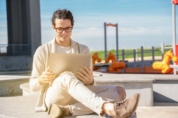 young man working from home on laptop outdoor stock photo